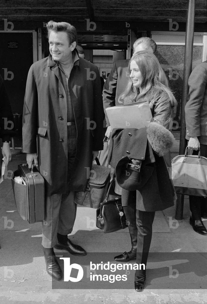 American country singer Johnny Cash with his wife June Carter arriving at Heathrow Airport from New York. 2nd May 1968 (b/w photo)