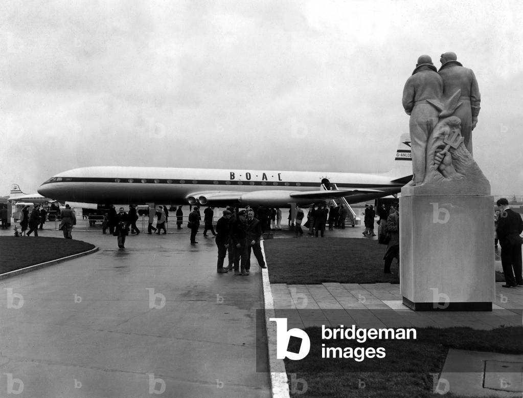 The De Havilland Comet 3 airliner of the B.O.A.C. airline, arrives at London Airport after completing a 30,000 mile globe circling flight piloted by De Havilland's chief test pilot John Cunningham and his assistant Peter Bugge. Looking on is the memorial to Sir John Alcock and Sir Arthur Whitten Brown who made the first non-stop transatlantic flight 28/12/1955 (b/w photo)