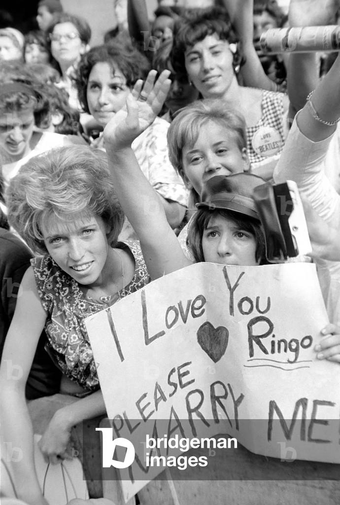 Screaming Beatles fans cheer for their idols on the streets of New York City, USA as the British pop group arrive for their American tour. 
August 1964