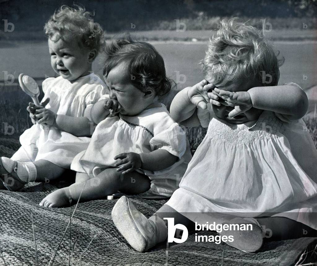 Prizewinners in a baby beauty parade at the Windsor Reperatory School in Windsor sit together after the show, with the baby on the end crying. June 1952