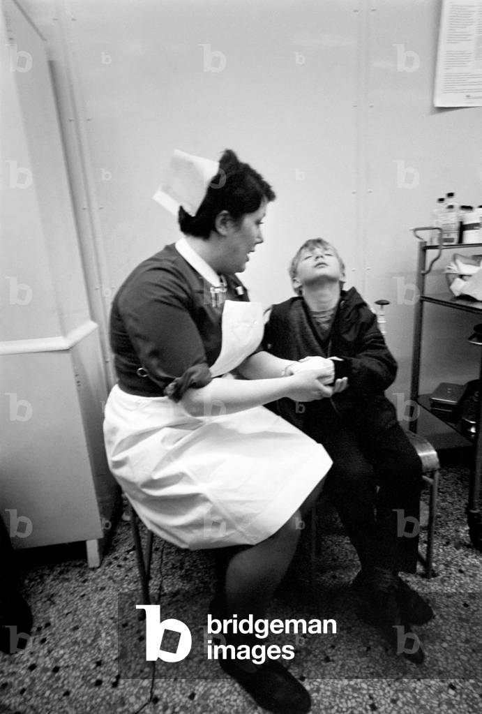 A young boy witha an injured hand gets treatment ffrom a nurse Eliat the hospital 
November 1969