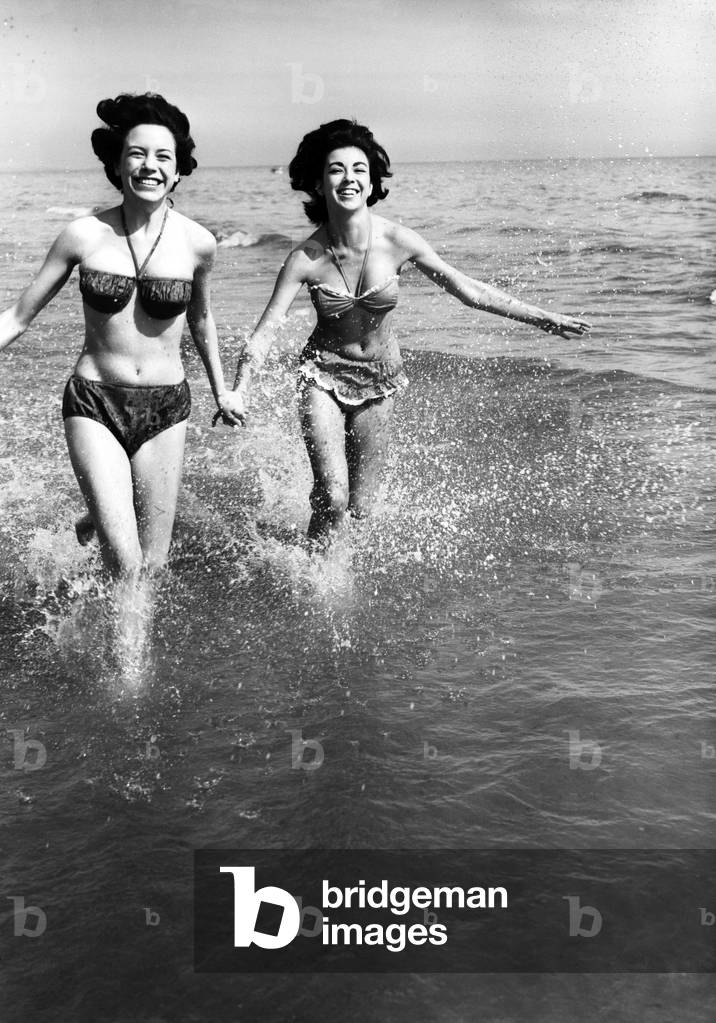 Hot weather scenes in Margate, Kent. Two young women running in the sea. 30th June 1961 (b/w photo)