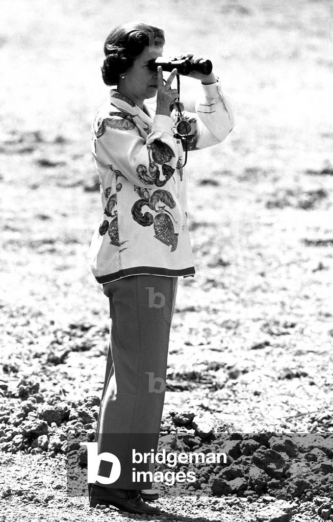 Queen Elizabeth II looking through a pair of binoculars and sticking two fingers up, 1979 (b/w photo)