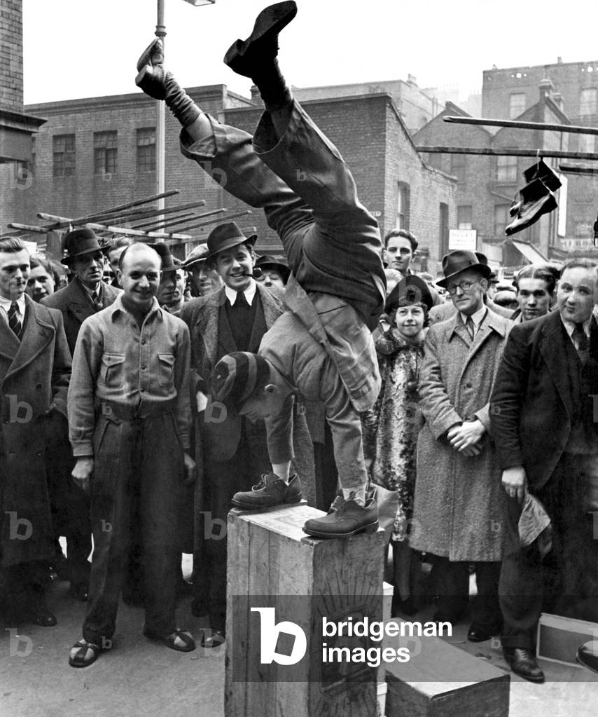 Sunday morning in Petticoat Lane. Seen in the boot market. Proving his shoes won't skid. 28th February 1939 (b/w photo)