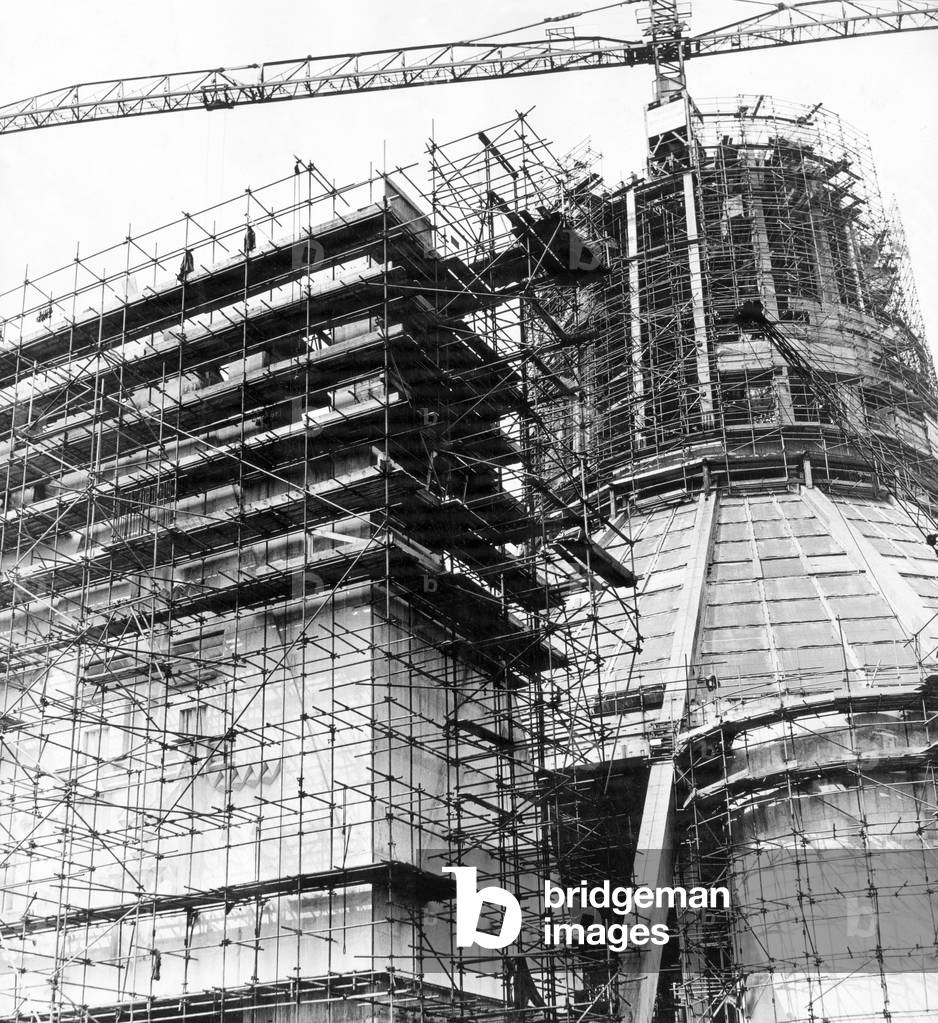 In a web of steel scaffolding, the main entrance to the Liverpool Metropolitan Cathedral rises alongside the central structure, already a dominating feature of Liverpool's skyline. 11th June 1965 (b/w photo)