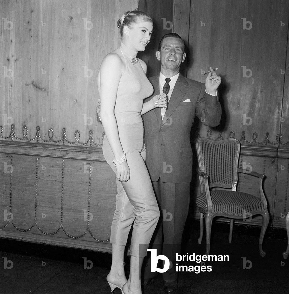 Actor and comedian Norman Wisdom enjoys a cup of tea with actress Anita Ekberg at the savoy Hotel, May 1956 (b/w photo)