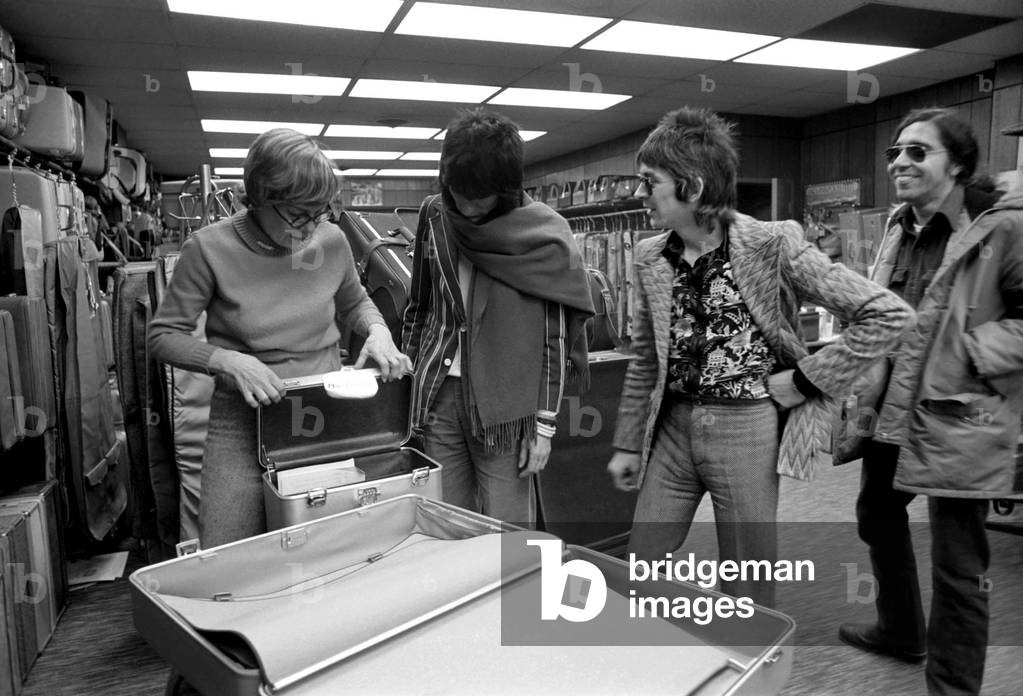 Rod Stewart and The Faces tour of America. Ronnie Wood choosing a suitcase in a shop April 1975