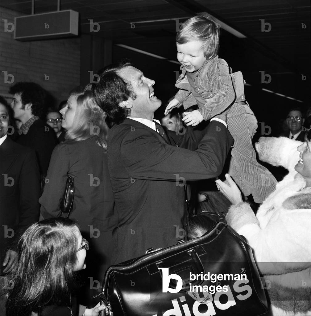 England Cricket: Mike Denness. MCC Cricket Team arrive home after their tour of Australia and New Zealand. Mike Denness holding up 21 month old Craig, March 1975 (b/w photo)