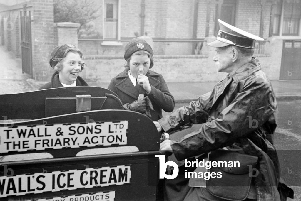 Wall's Ice Cream man seen here on his tricycle serving two schoolgirls
Circa 1939
