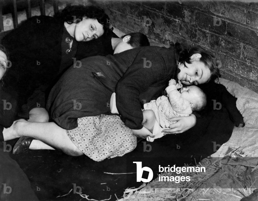 A Mother protects her baby whilst taking cover from air raid in a farmer's barn. September 1941