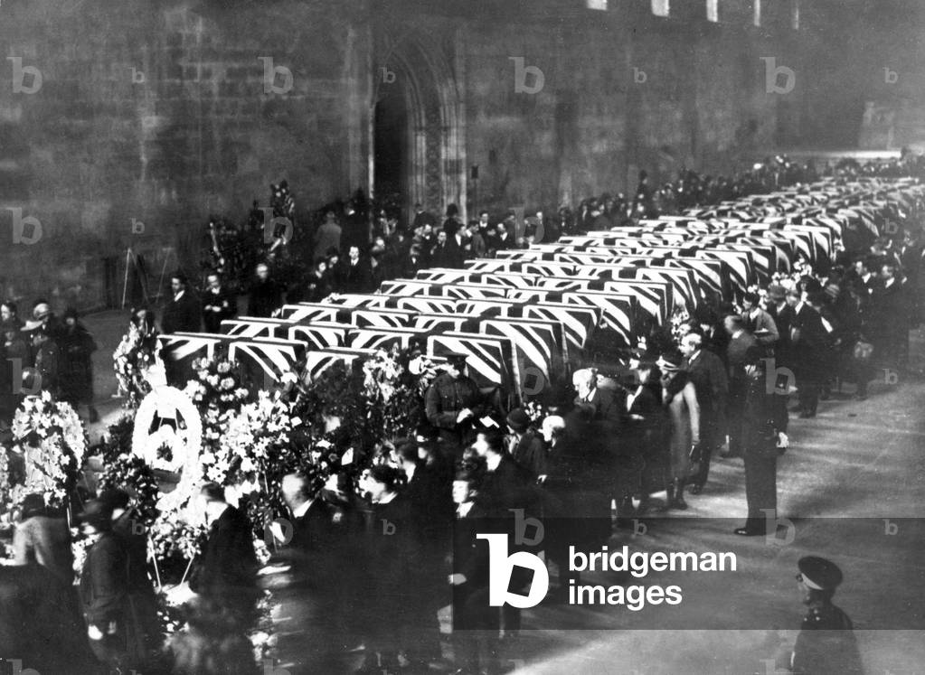 The sad and impressive scene at historic Westminster Hall when the coffins of the forty-eight men killed in the R101 disaster lay in honoured state. As officer and men of the R.A.F., the latter with arms reversed, kept motionless guard beside the biers, around which were hundreds of beautiful wreaths, with that sent by the King and Queen at the head. An endless stream of people, numbering many thousands, passed in silent homage through the dimly-lit hall and paused reverently around the coffins, each of which was covered with the Union Jack., 10th October 1930 (b/w photo)