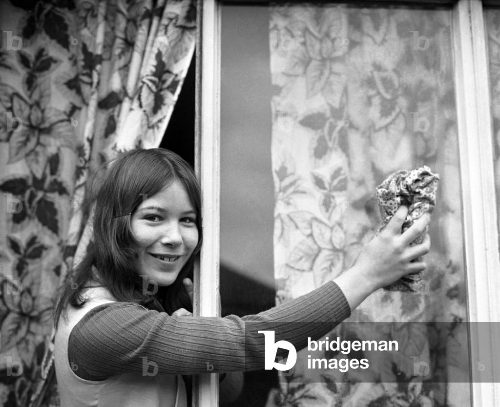 Domestic Life: Teenager Jeanette Green doing household chores at her home - here cleaning the windows. December 1969