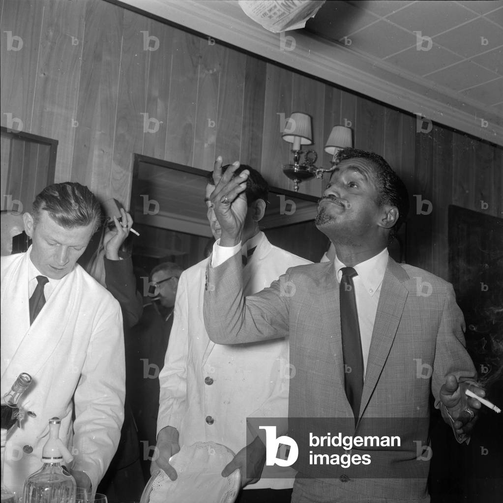 Sammy Davis Jnr at the Mayfair Hotel throws a paper in the air after reading 'the so called report of his marriage break-up, 3rd May 1966 (b/w photo)