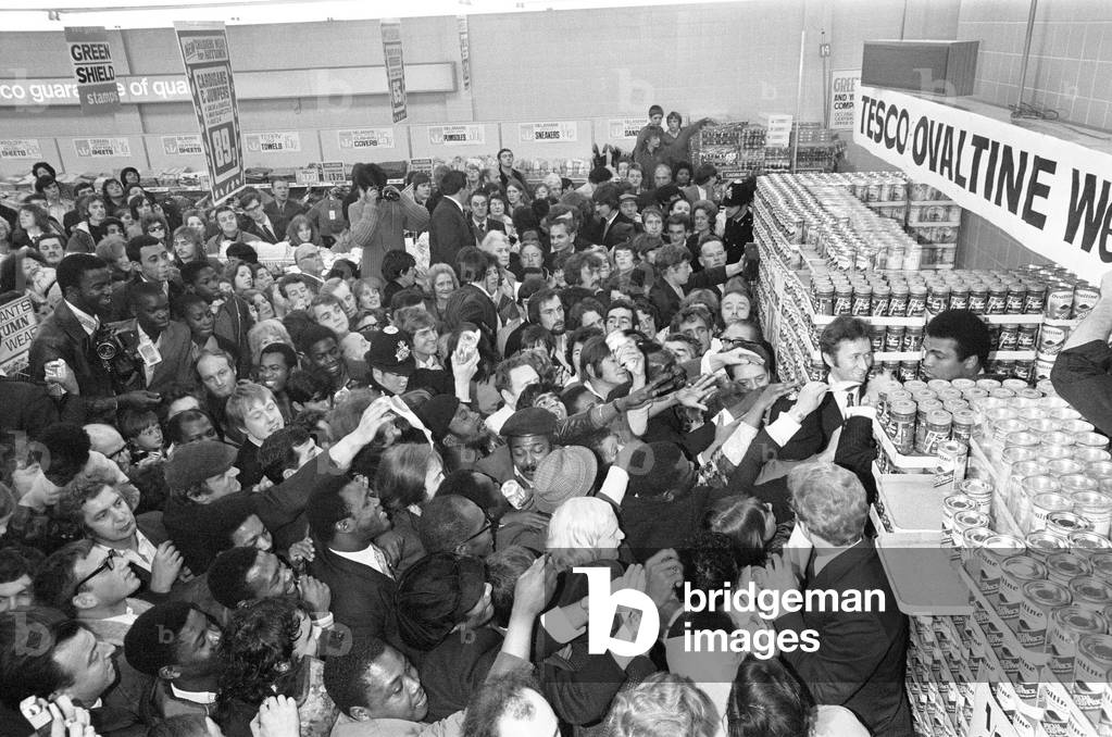 Muhammad Ali at a supermarket in Stretford to promote Ovaltine gets cornered by loads of fans wanting autographs. Police had to move in to call it off, 11th October 1971 (b/w photo)