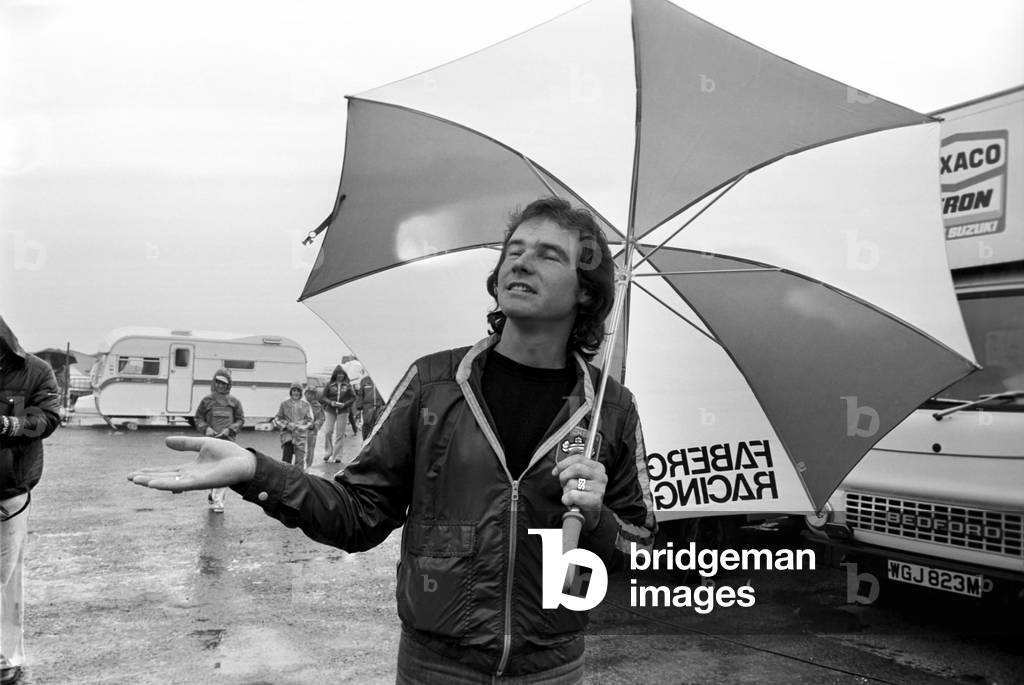 John Player British Grand Prix, Silverstone. Barry Sheene with umbrella in the rain, August 1977 (b/w photo)