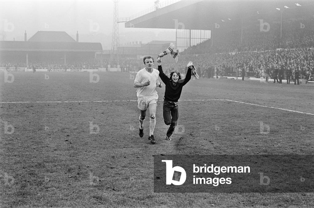 FA Cup Quarter Final match at Elland Road. Leeds United 2 v Tottenham Hotspur 1 Young Leeds fans runs onto the pitch to celebrate victory at the fianl whistle as Billy Bremner makes his way off, 18th March 1972 (b/w photo)