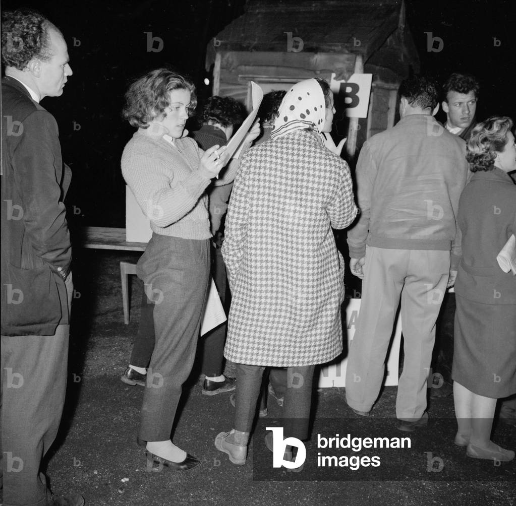 British racing drivers Pat Moss and Ann Wisdom check in looking tired after finishing the International RAC rally at Crystal Palace, 23rd November 1959 (b/w photo)