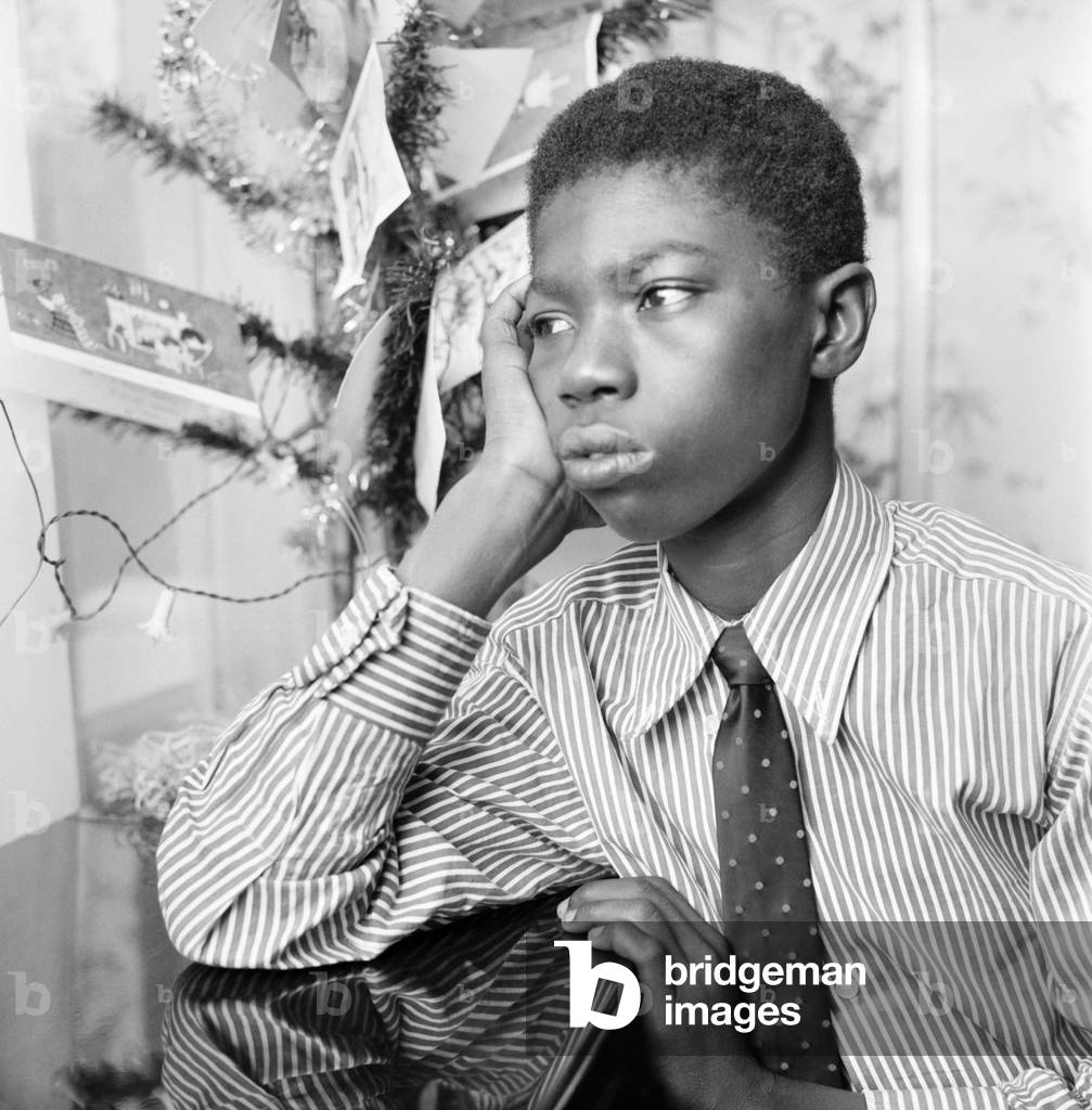 Pictured at his sister's home in Ilford, 13 year old Ebenezer Baidoo waiting by the window hoping for a call to say he may remain in Britain. 
December 1969