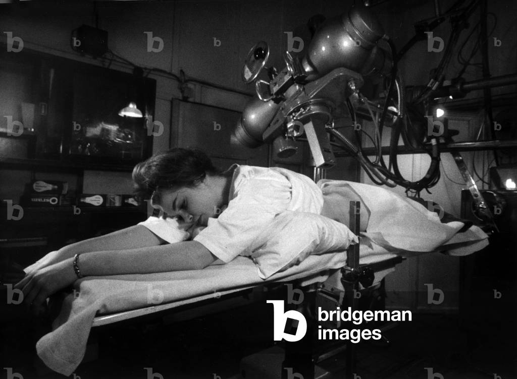 Woman undergoing a cancer check at an X ray unit in a London hospital. It is fitted with a unique prototype tracking system that allows healing rays not only to penetrate deep into the body to the root of the cancer, but also to trace automatically along the growth's spreading tentacles. January 1963 (b/w photo)