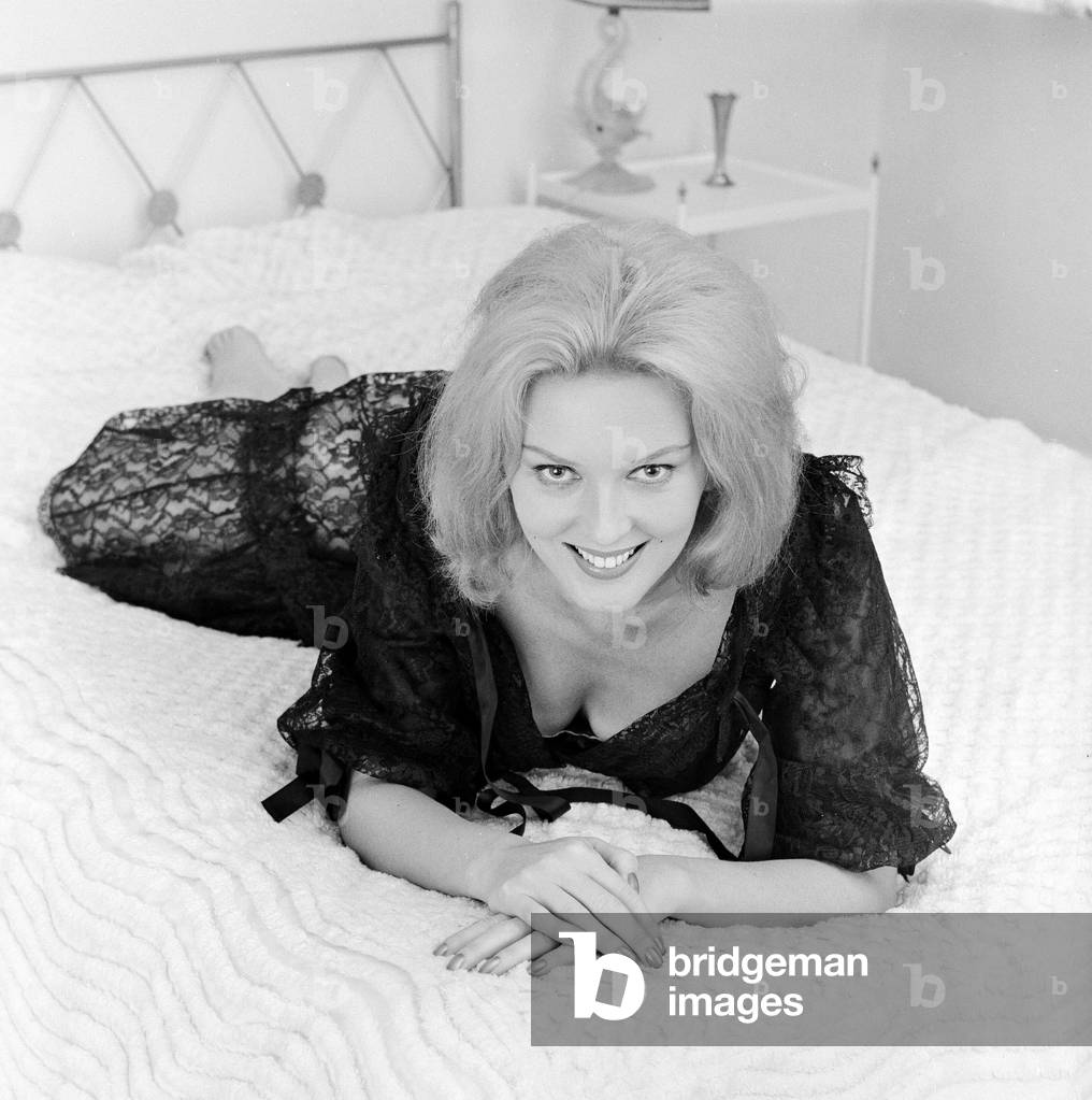 Woman modelling Lingerie on a bed, 1964 (b/w photo)
