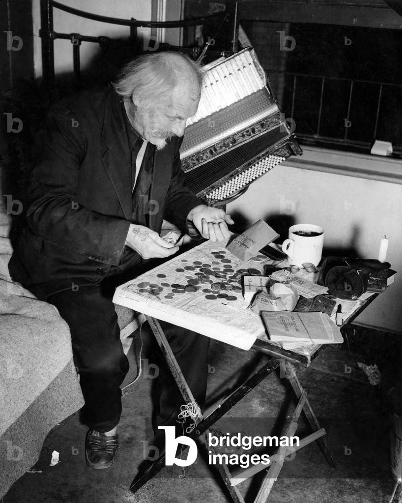 Buskers: Each night in his lonely bedroom, Gus Andrews counts the receipts for the day. October 1947 P018617