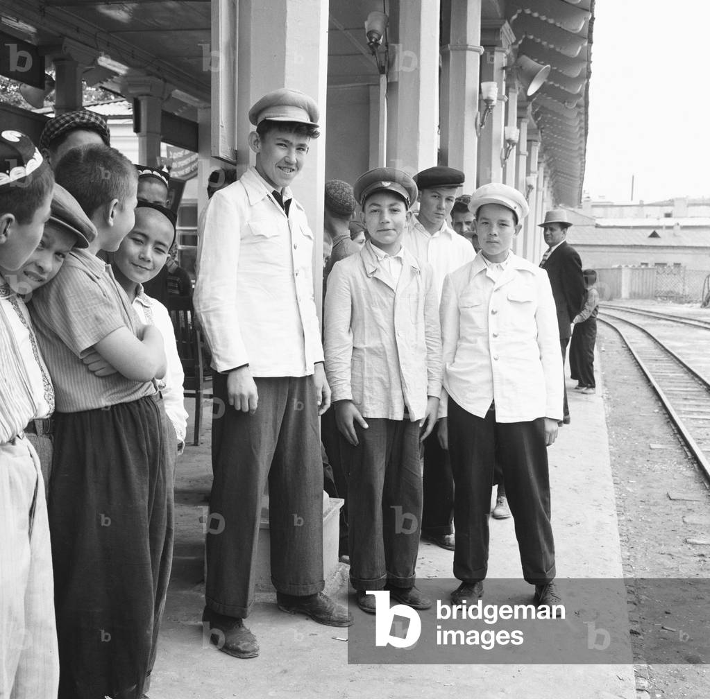 Teenage boys seen here waiting on the platform of an un-named town in central Russia. The boys are dressed in the uniforms of railway porters. 25th May 1960 (b/w photo)
