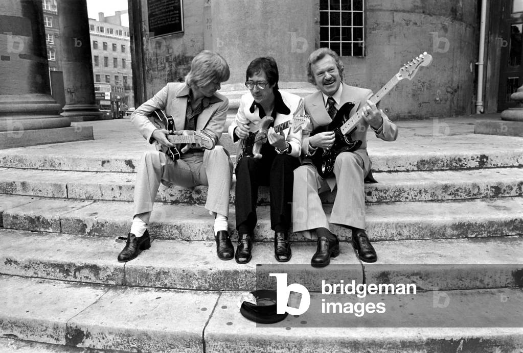 Singing in the street are left to right: Joe Brown, Hank Marvin, Bert Weedon, August 1977 (b/w photo)