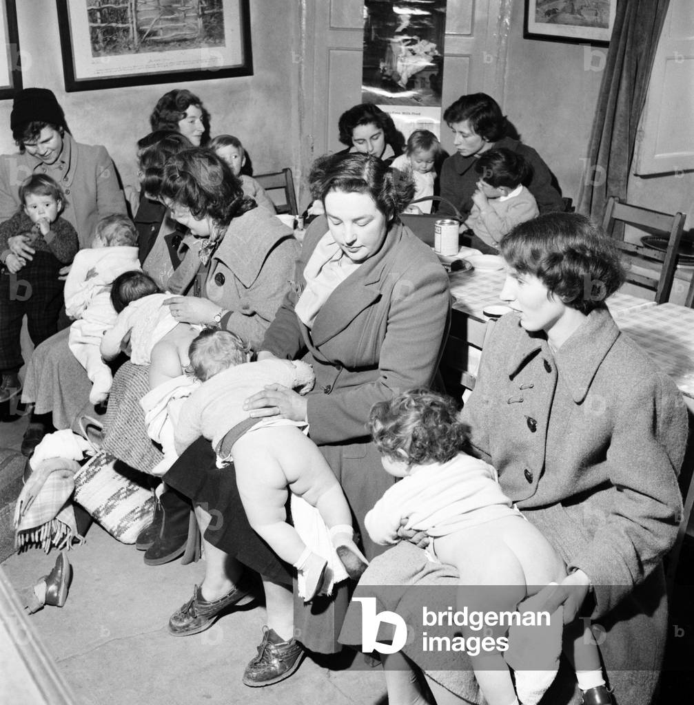 Medical Baby Clinic: Once every week the Falklands Arm pub near Stratford stops serving beer and becomes a baby clinic. Where mums can bring their babies to be clock by the doctor and to hare a cup of tea and a gossip, March 1958 (b/w photo)