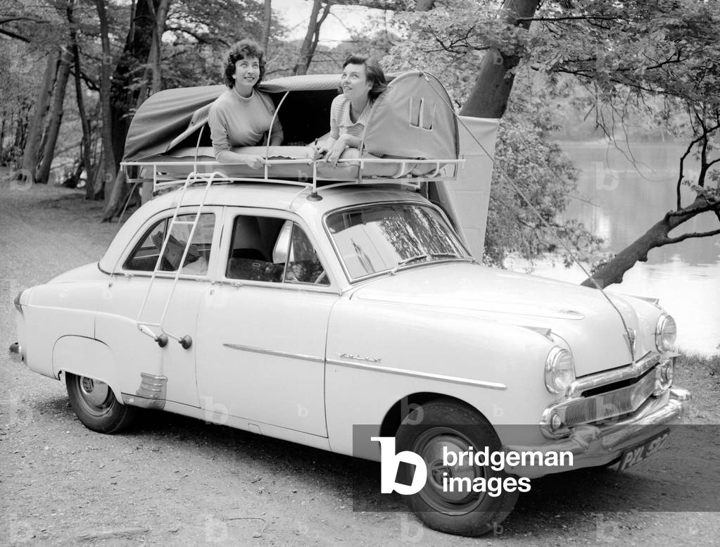 Our two reveille models keep an eye on the unpredictable English weather as they demonstrate the new car rack tent, designed so it can be assembled in minutes 
May 1956