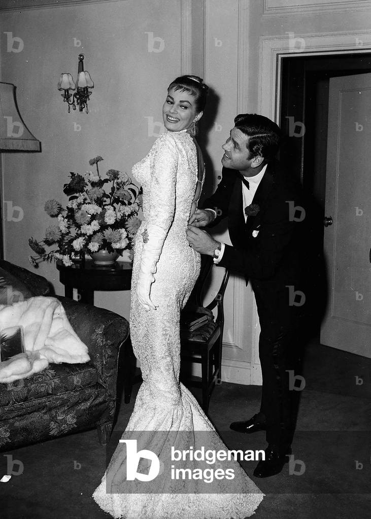 Actress Anita Ekberg has her dress zipped up by her husband Anthony Steel October 1956 (b/w photo)