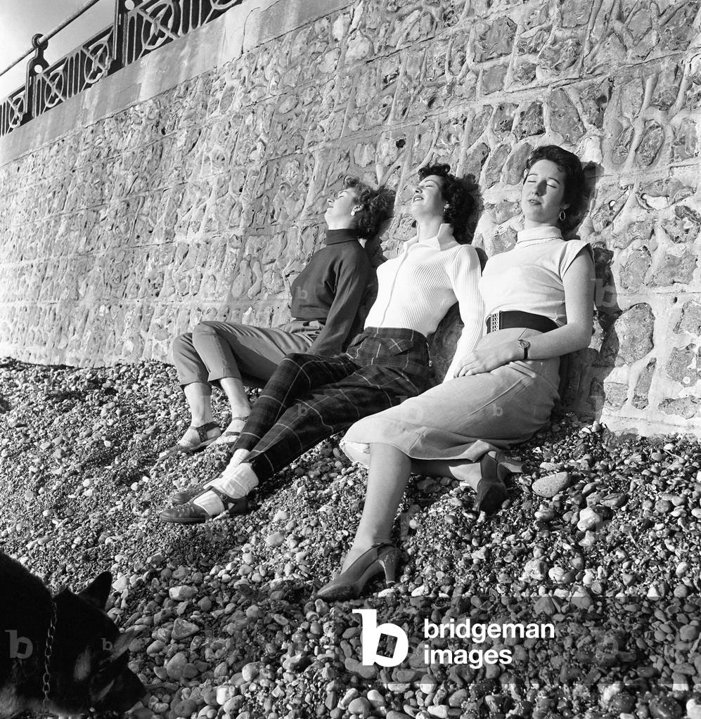Three young women enjoy the winter sun, Brighton, East Sussex. (Left to right) Mary Cammack, Pamela Hyams, Jill Bennett. December 1953 (b/w photo)