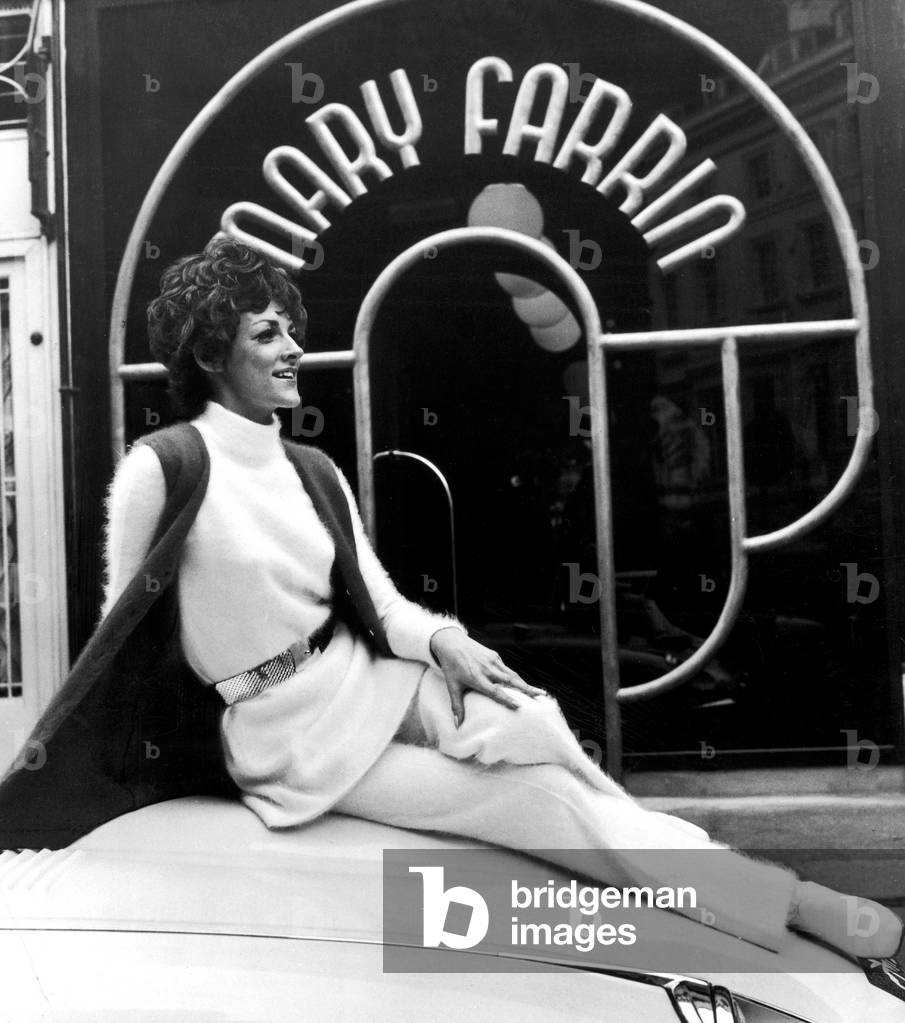 Fashion designer Mary Farrin wearing her own white knitted angora dress over matching trousers with scarlet waistcoat from her boutique on South Molton Street. London.
9th March 1969.