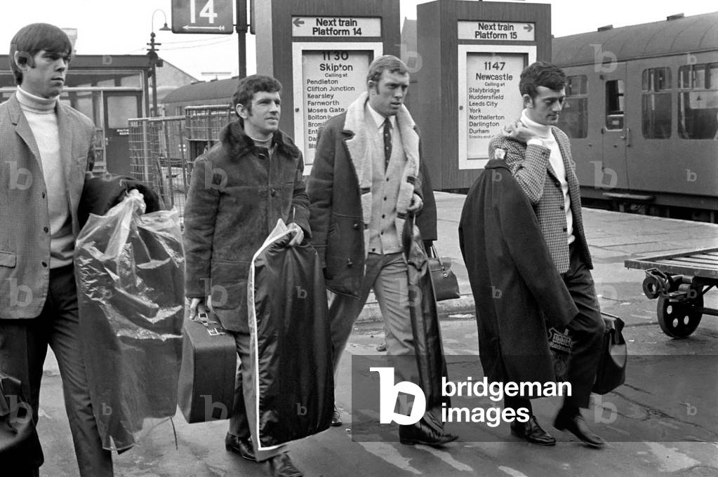 The destination is a little further afield than Skipton which shows on the Victoria Station directory board in pic, for these Leeds players. They were on route from Leeds to Budapest, and had just arrived in Manchester, on their way to Ringway, to fly to Budapest. Left to right David Harvey, reserve goalie, Johnny Giles, Mick Jones, and Terry Hibbit leave the train at Victoria. December 1969 (photo)