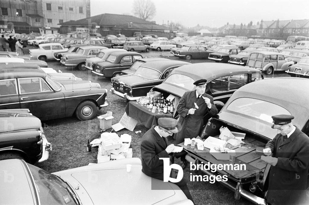 Chauffeurs enjoy a spot of lunch in the West Car Park at Twickenham whilst their employers watch Varsity rugby match. 8th December 1967 (b/w photo)
