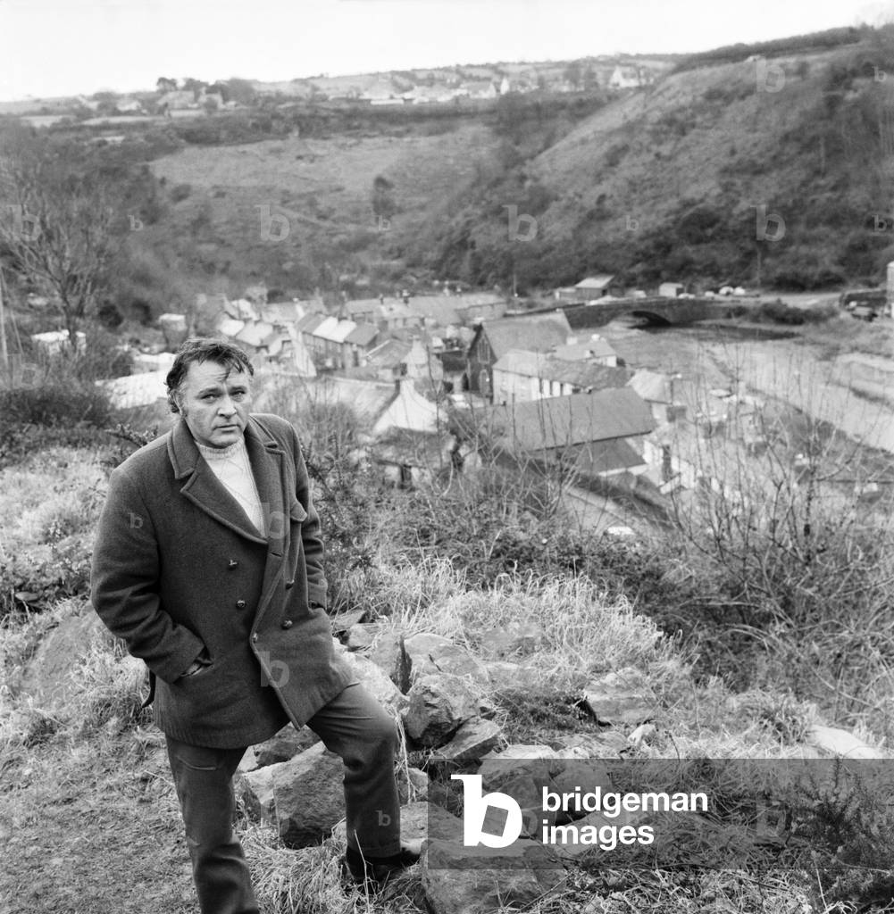 The locations for the film 'Under Milk Wood', depict the Welsh village of Llaregub, So there in the village of Bugerall, Richard Burton contemplates the scene. Fishguard is the location for this fictional Welsh village. General scene taken on the hill overlooking the village of Llaregub (Fishguard), at the Druib Stone Circle, the actual spot referred to by Dylan Thomas in his play, and used as a location in the film. February 1971 (b/w photo)