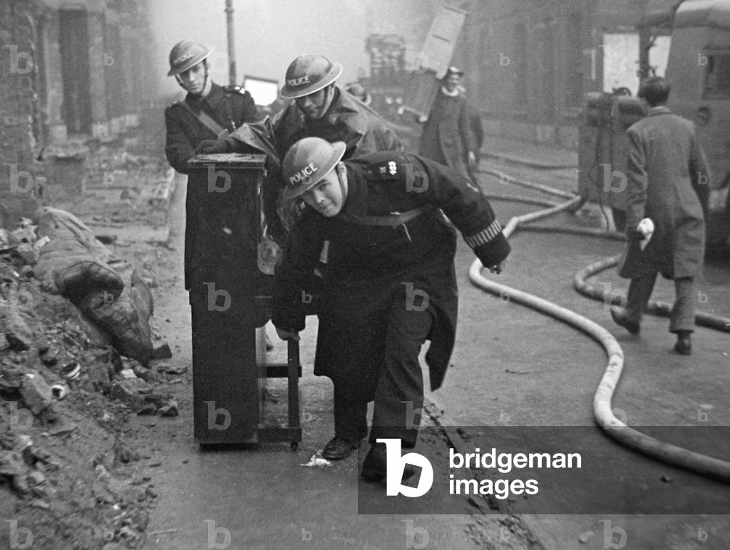 Policemen with a piano help salvage furniture following a V2 attack on Woodbine, 3rd February 1945 (b/w photo)