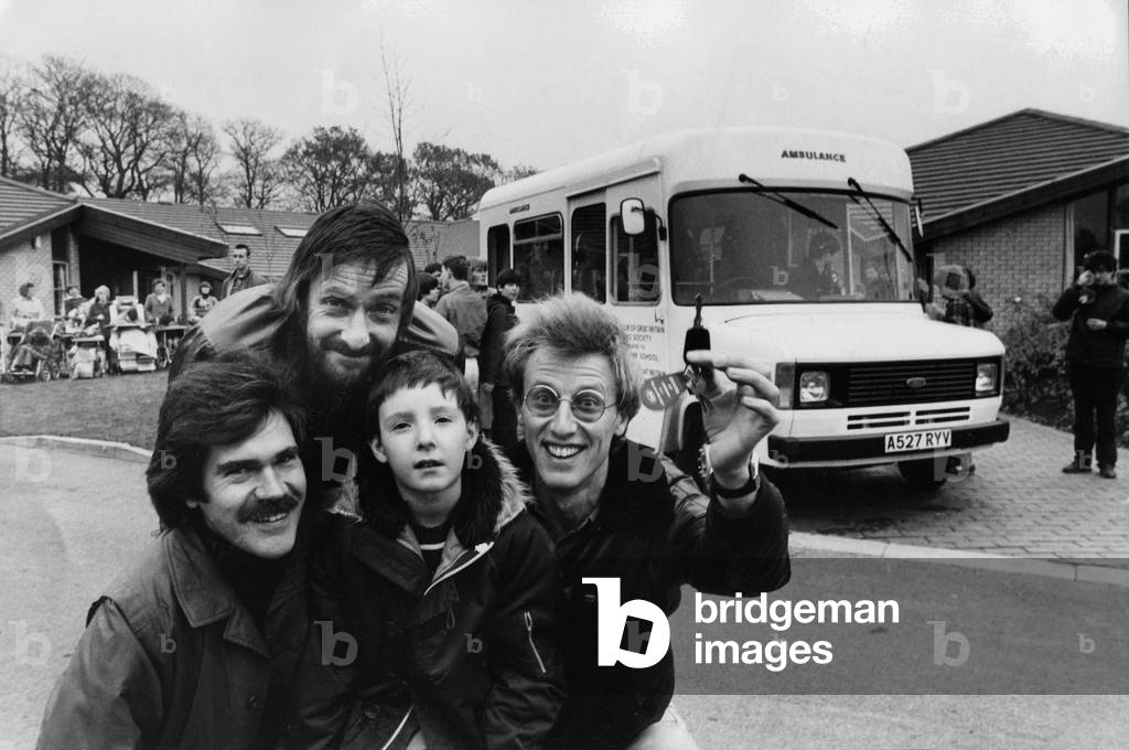 Three members of pop group Lindisfarne visit Trouts Lane Special School, in Durham City, to hand over a £15,000 Sunshine Coach on behalf of the Tyneside committee of the Variety Club of Great Britain. Pupil Thomas Dean pictured with (left, to right) Ray Jackson, Alan Hull and Ray Laidlaw. 07/11/83.