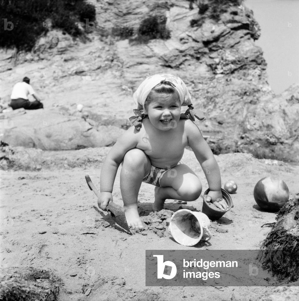 Lovely little Bronwen Harlow aged 3 of Nottingham on a Cornish holiday with her parents, happily digs sandcastles on Porth Towan Beach. Mummy tied her long blonde hair in pigtails to keep it out of the sand.
 June 1960