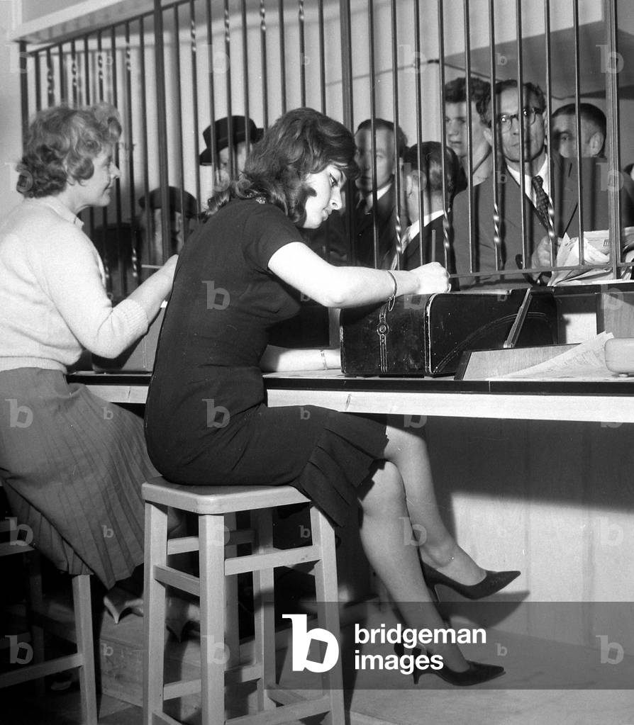 Bookies clerks taking bets from punters at a busy betting shop in Soho, London
May 1961