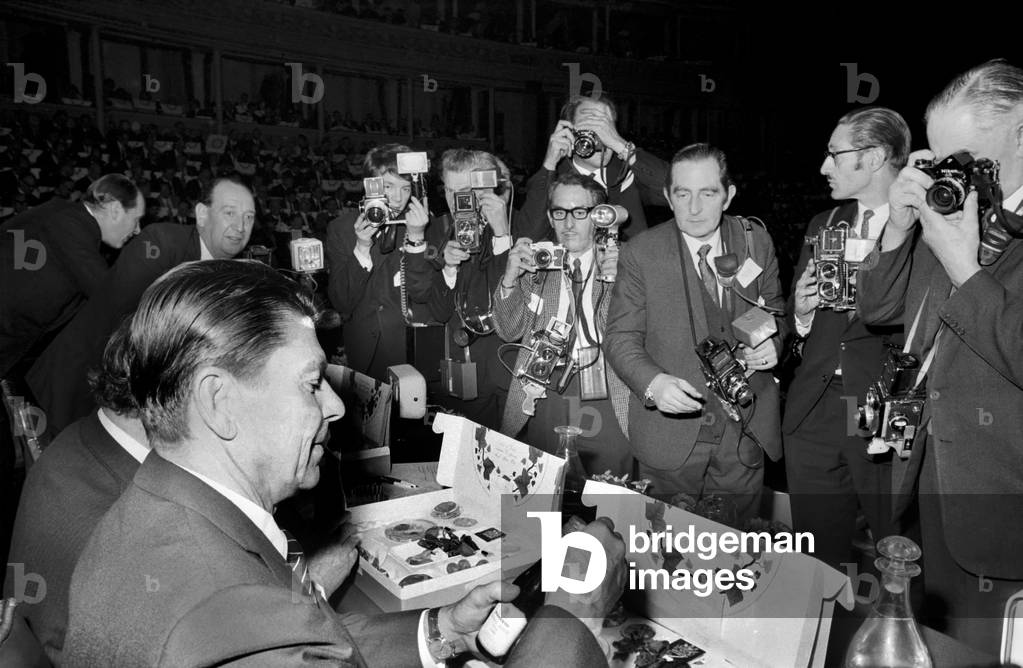 The Institute of Directors annual conference at the Albert Hall, more improperly known as 'The Picnic' from the practice of serving lunch in picnic boxes to the 3,000 odd, directors who attend, was addressed today by such diverse speakers as Barbara Castle, Ronald Reagan, Governor of California, Ian McLeod and John Betjeman. 
How to have a peaceful lunch - Governor Ronald Reagan tucks into his picnic box while photographers picture every bite. November 1969