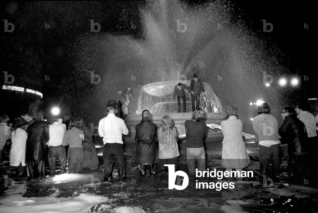 People sing and hold hands in the fountains in Trafalgar Square as midnight strikes. 
January 1970