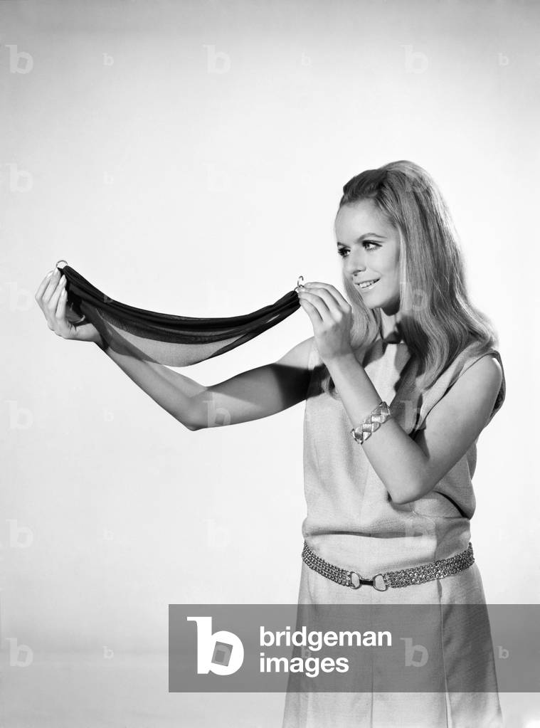 Fashion: Hair Styles: Woman demonstrating how to use a Alice Band. Model: Anne Maria Greeber. 1966 (b/w photo)