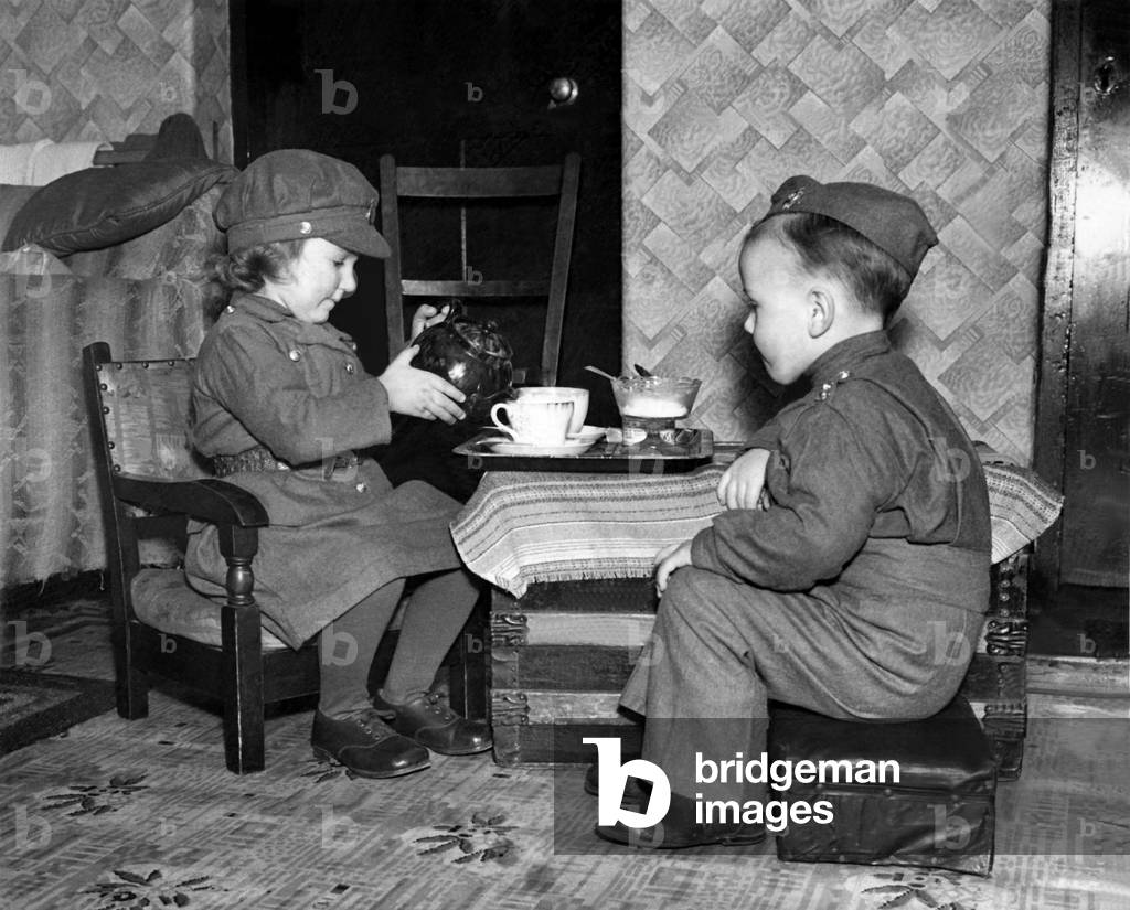 War children
A small girl dressed in the uniform of the ATS is seen here pouring tea for a small boy in the unifom of a British soldier. January 1940 P000054