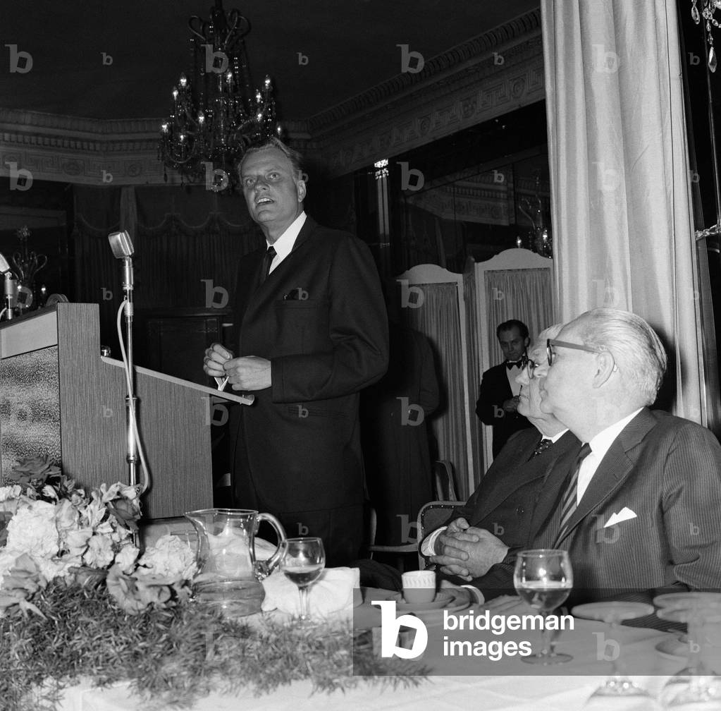 Billy Graham signs copies of his book 'World Aflame' at Foyles Literacy Luncheon held in the Dorchester Ballroom. The event was held in his honour. 30th June 1966 (b/w photo)