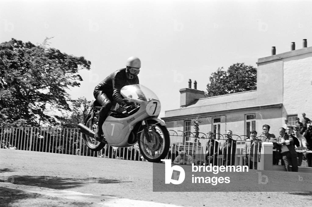 Isle of Man TT Races - Junior International. Jim Redman goes over Ballaugh Bridge. 16th June 1965 (b/w photo)