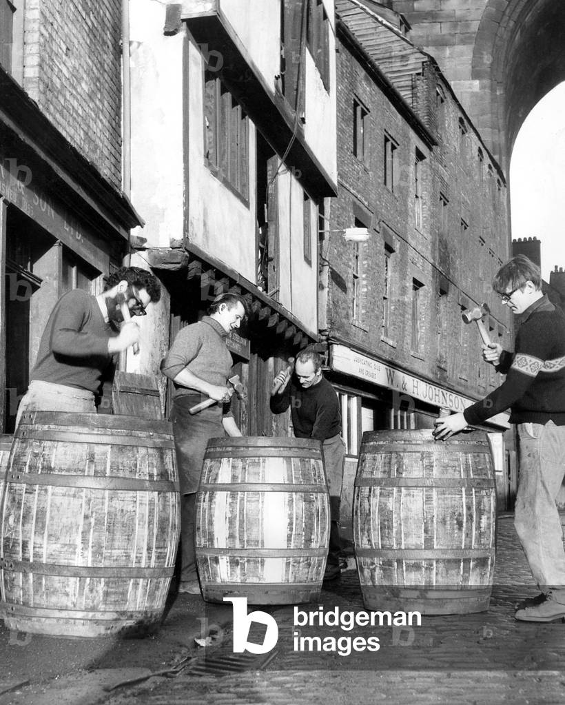 The ancient art of making barrels is demonstrated at The Close, Newcastle, where coopers are pictured with 56 gallon whisky hogsheads in the shadow of the High Level Bridge, 18 November 1969