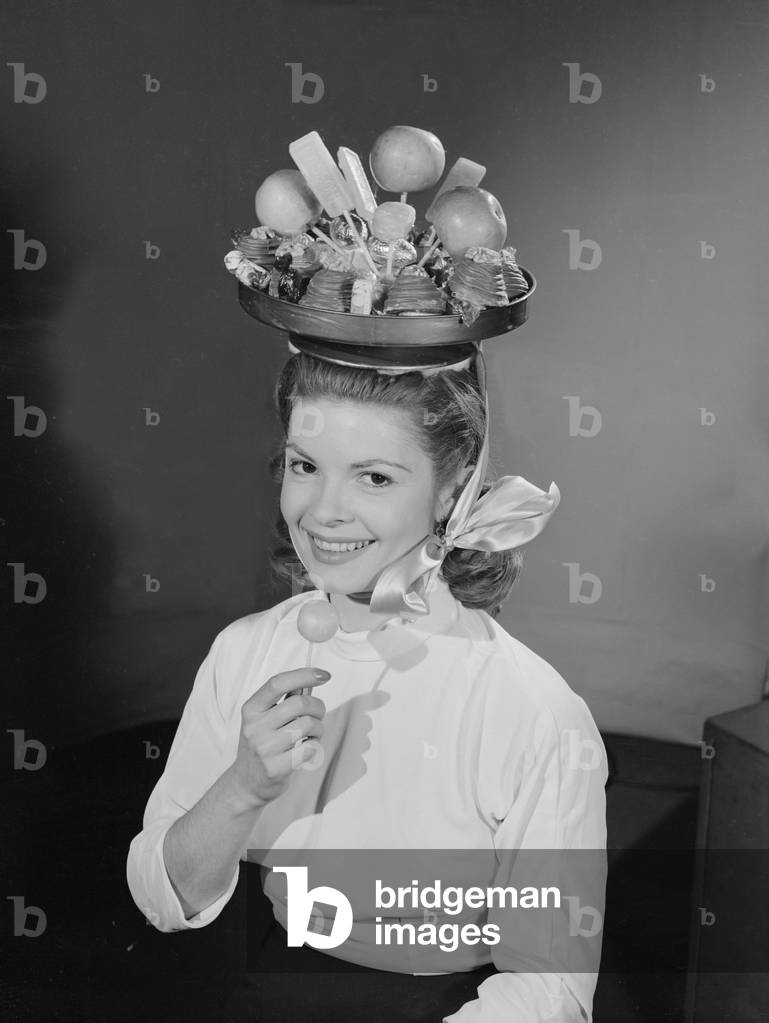 Model wearing a hat made from chocolate and fruit, c.1960 (b/w photo)