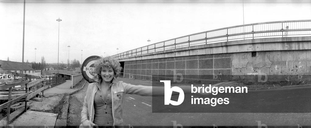 Model Angela Jay near her home in Hendon trying to stop a bus, 9th January 1975 (b/w photo)