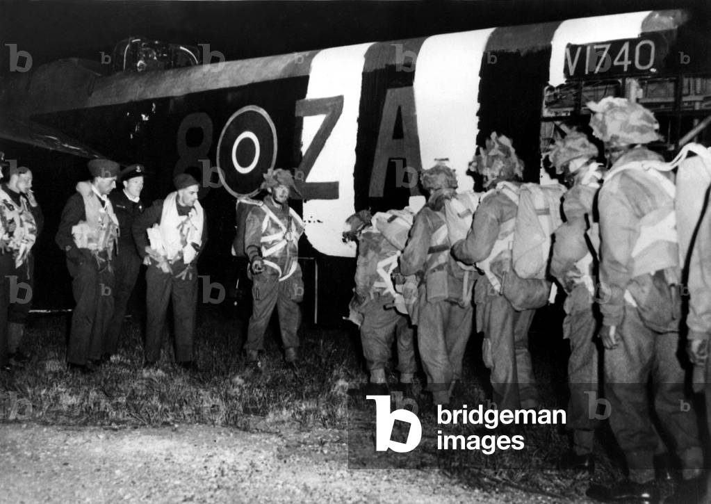World War Two - Second World War - British paratroopers, faces blackened and wearing camouflaged helmets, boarding their plane for their drop behind the German defence in Normandy at the start of D-Day. 6th June, 1944 (b/w photo)