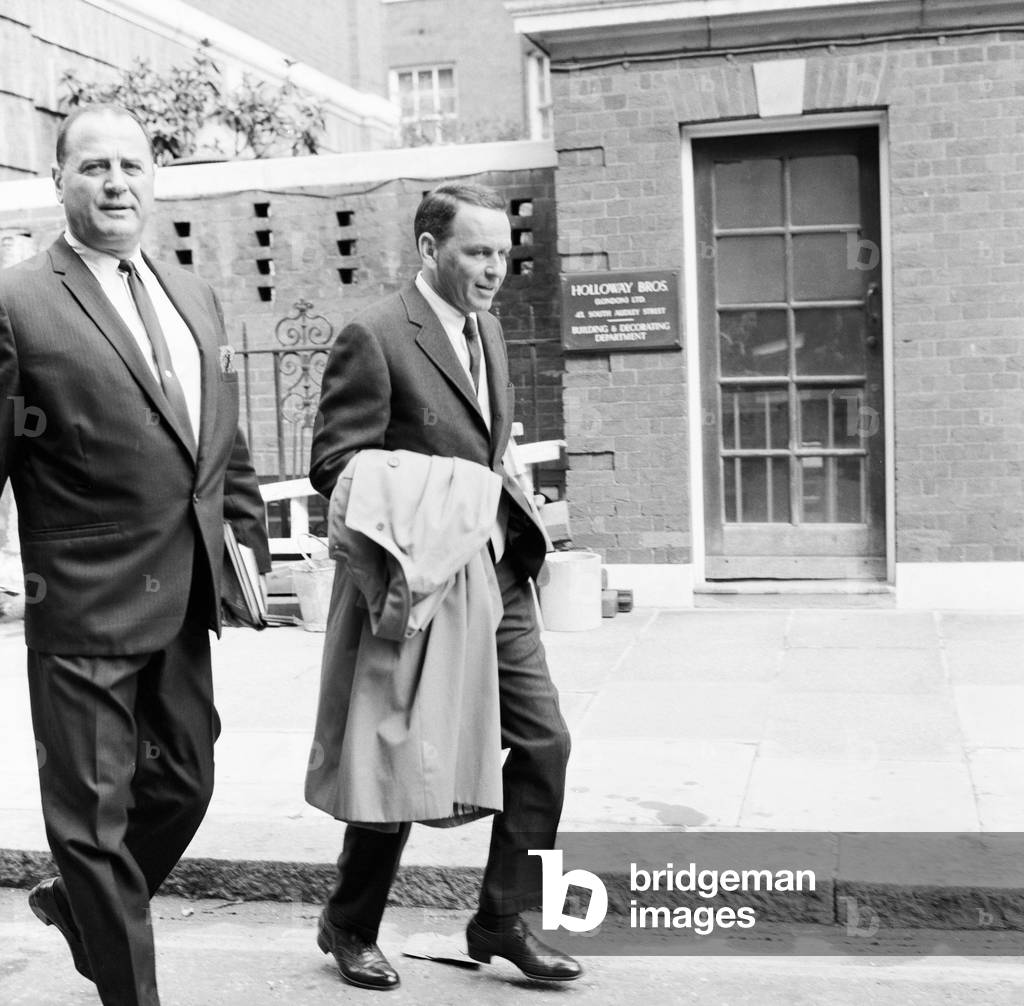 Frank Sinatra, pictured with Bradford Dexter, his business colleague and former actor, as they leave his apartment, via tradesman entrance, in Grosvenor Square, London, 1st August 1966.